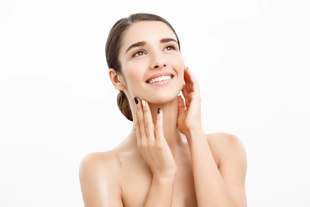 A smiling woman with smooth skin resting her hands on her face