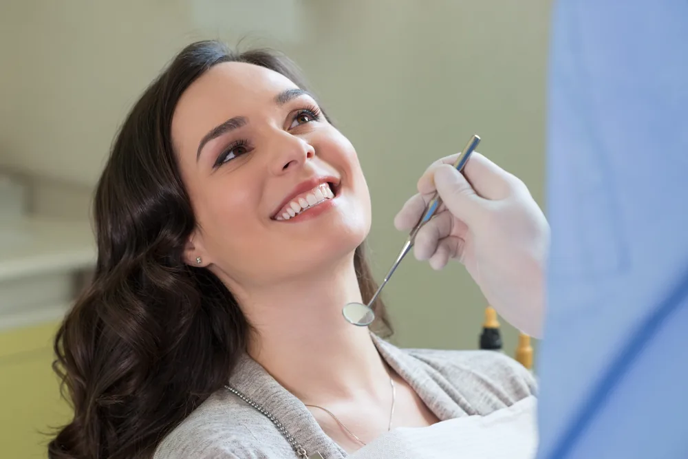 A smiling woman leaning back in the dental chair during a cleaning